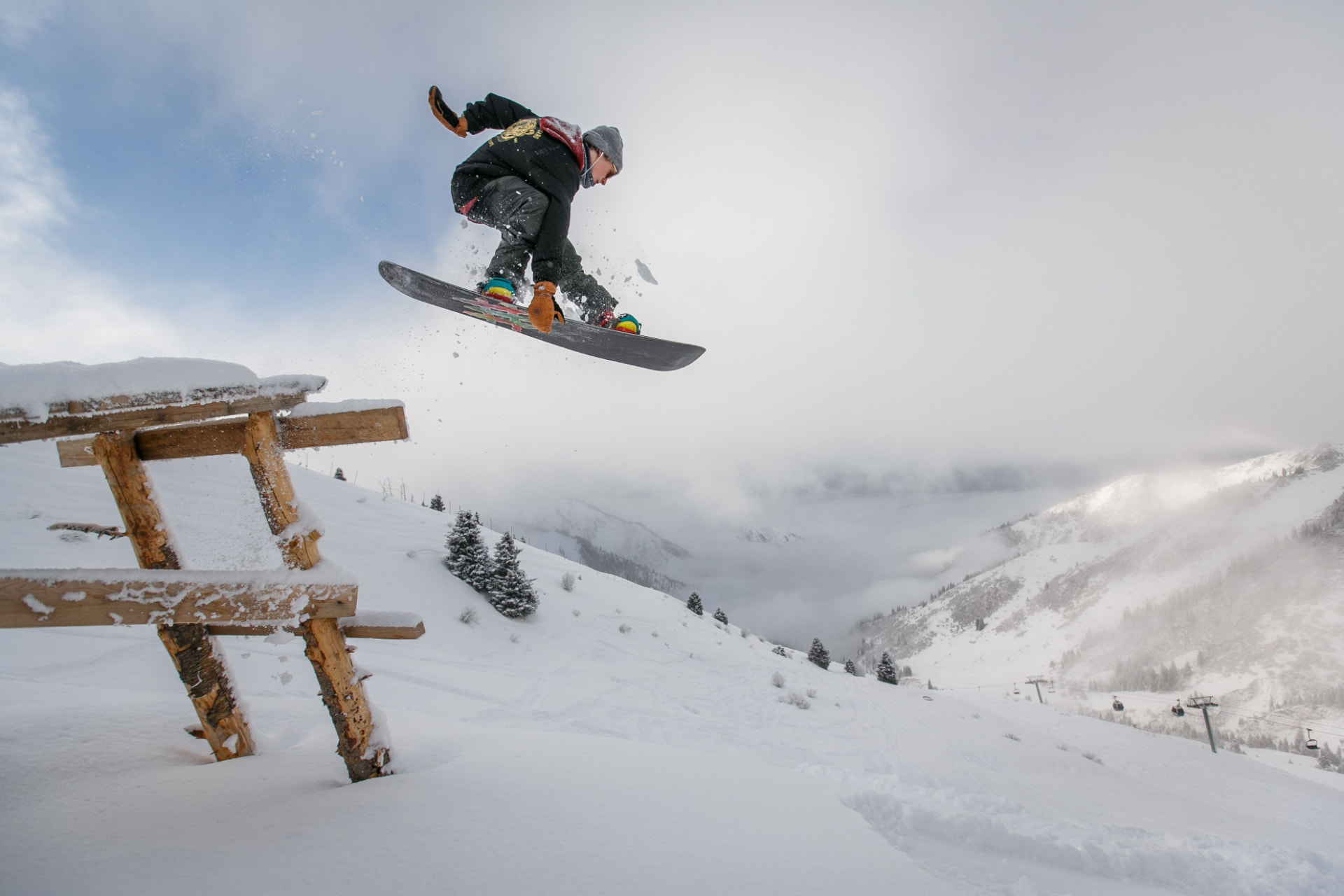 Snowboarder die met het board de lucht in gaat boven een houten schans