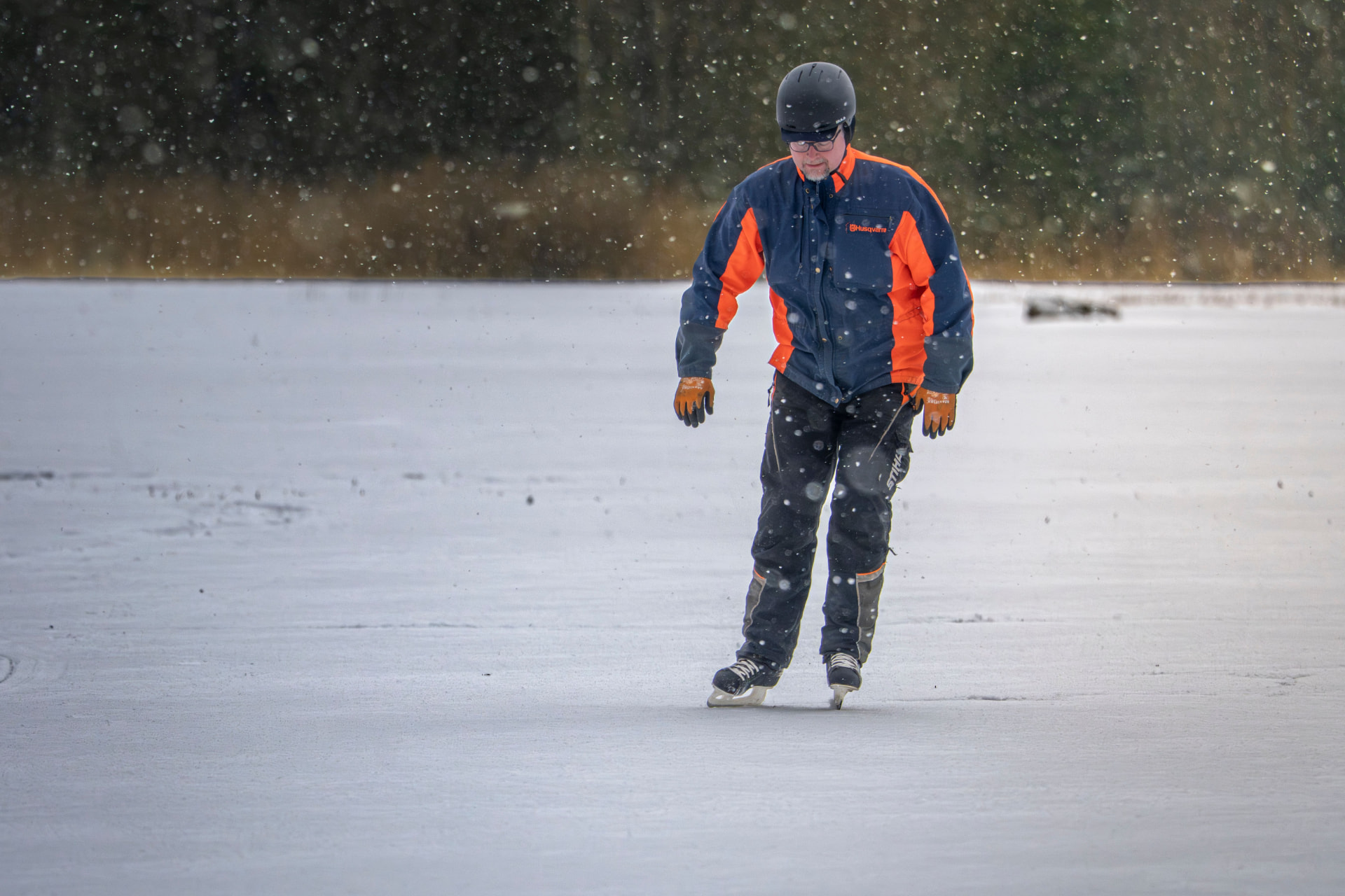 Schaatser met helm op een bevroren ijsvlakte tijdens lichte sneeuwval